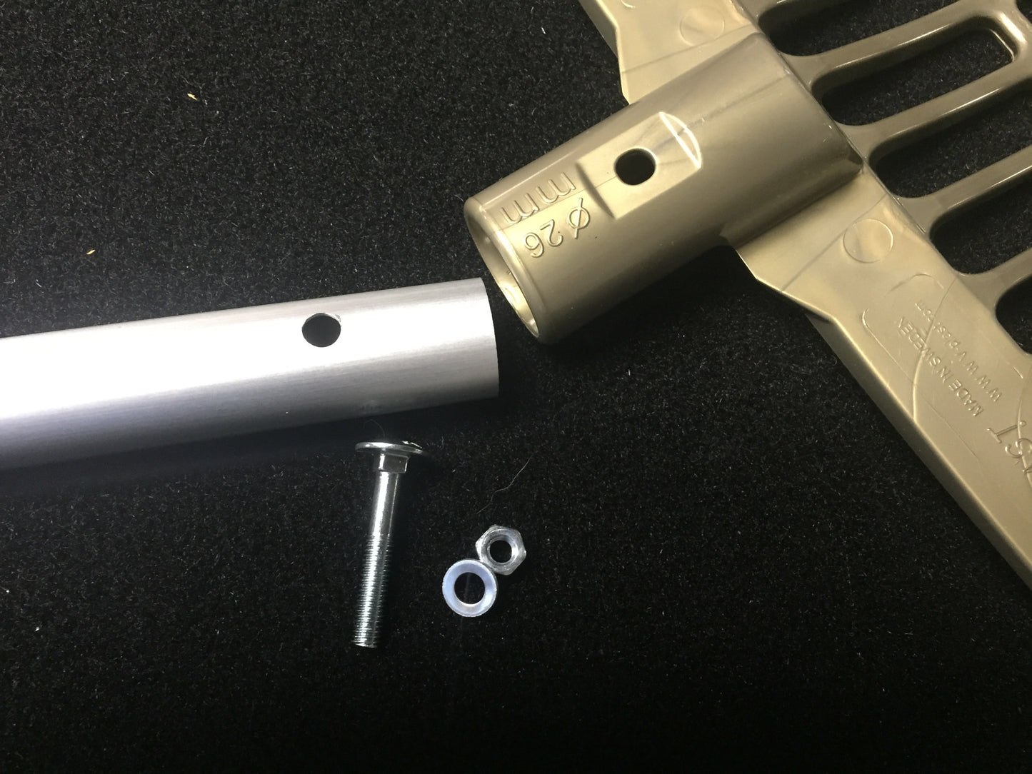 Hardware for Forever Fork Heads by Forever Fork—including a metal tube, rake head with marked connector, bolt, washer, and nut—is arranged on a black surface, ready for assembly.